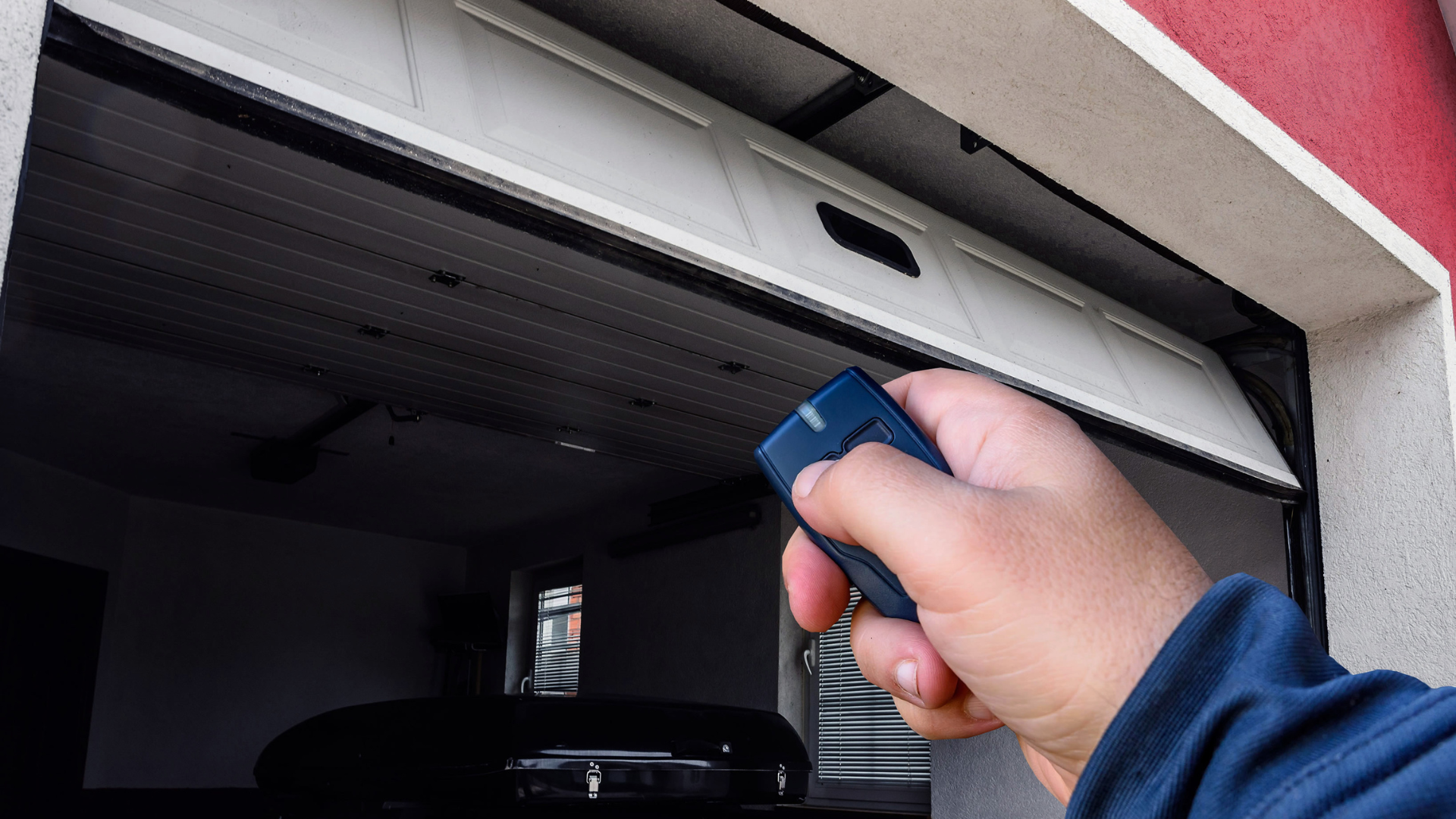 Hand holding a remote, opening a white garage door.