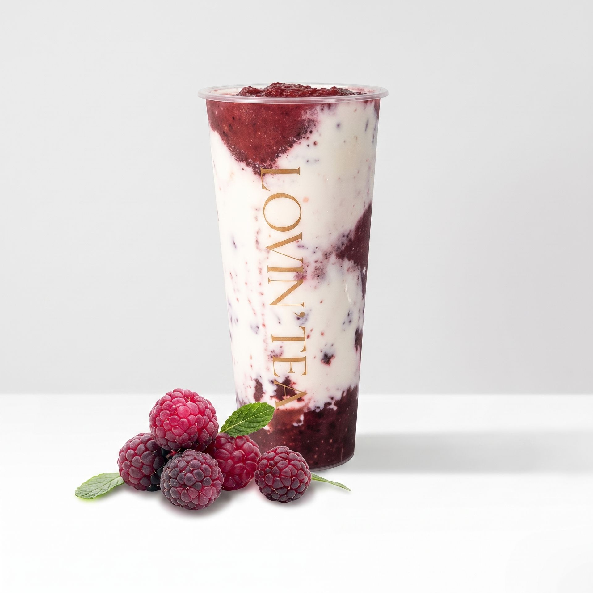 Berry parfait in a clear cup with yogurt and berries, topped with red berry sauce, beside fresh berries.