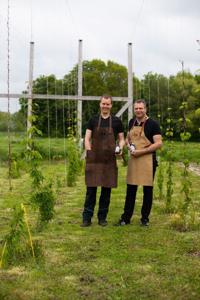 Twee mannen staan ​​in een veld met flessen bier in hun handen.