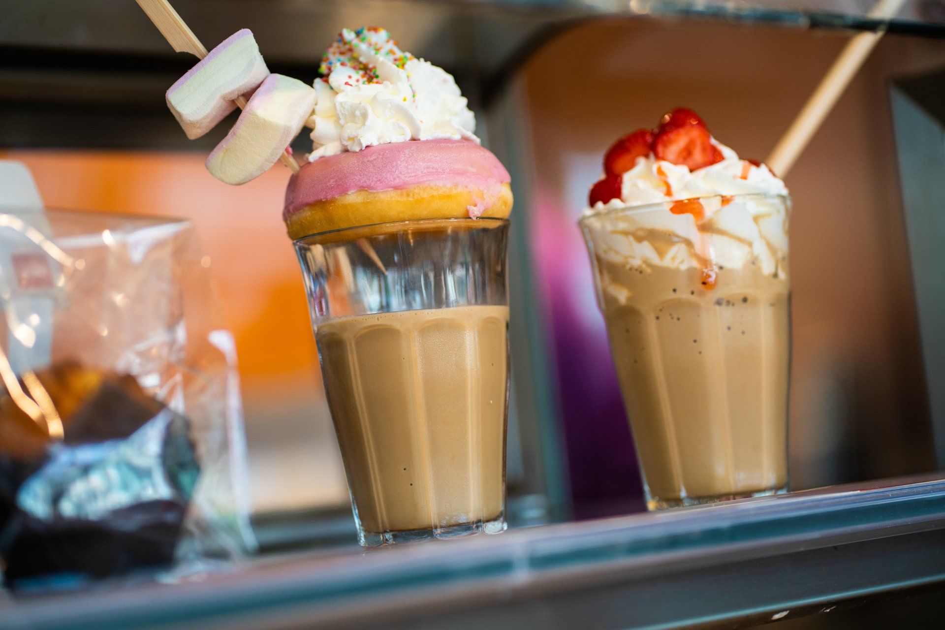 Op een plank staan ​​twee milkshakes met slagroom en aardbeien.