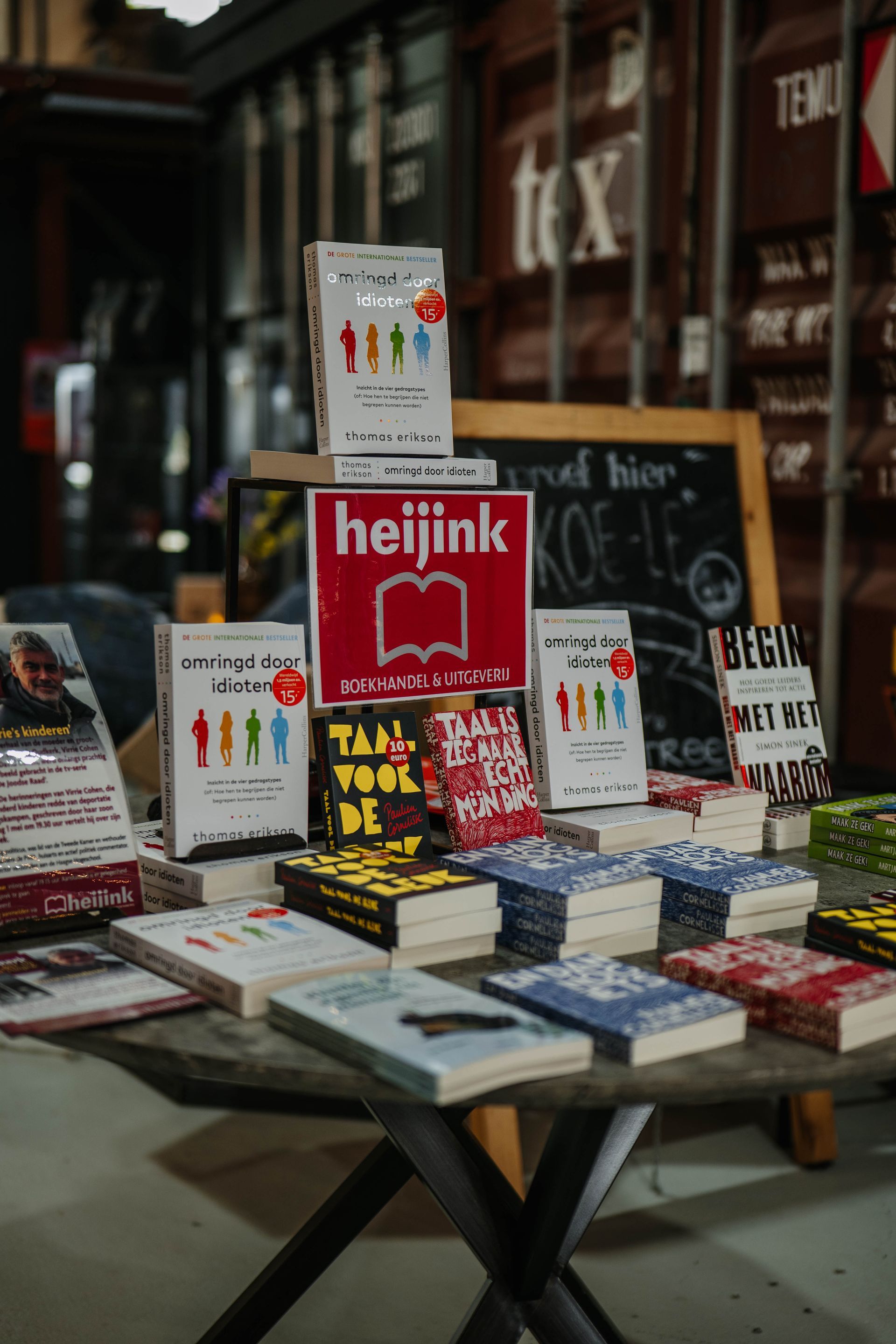 Een verzameling boeken op een houten tafel, met daarachter een rood 