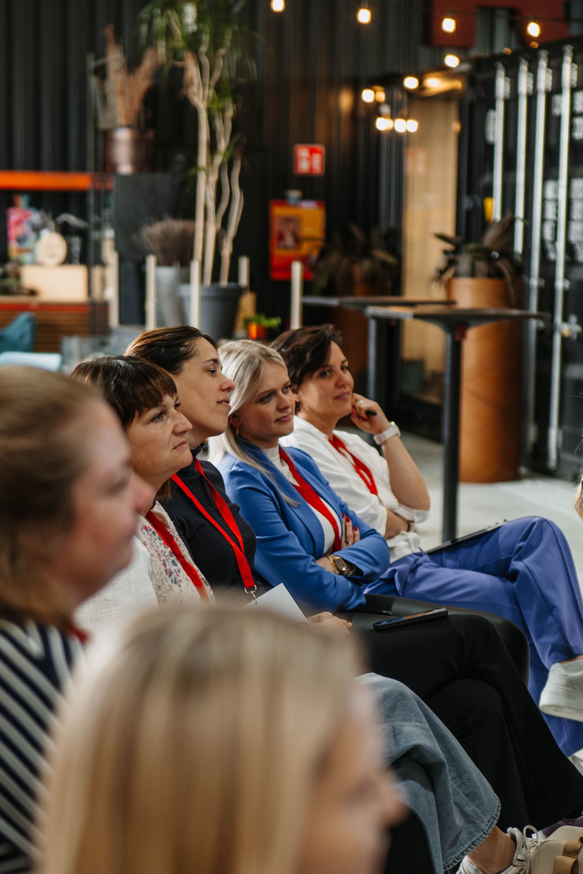 Een groep mensen zit in een binnenruimte en luistert aandachtig naar een spreker tijdens een professioneel evenement of workshop.