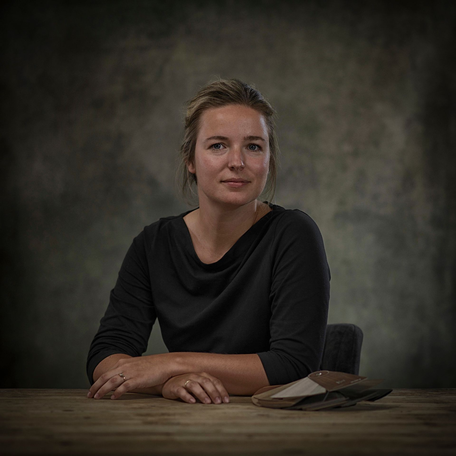Een vrouw zit aan een tafel met haar handen op haar knieën.