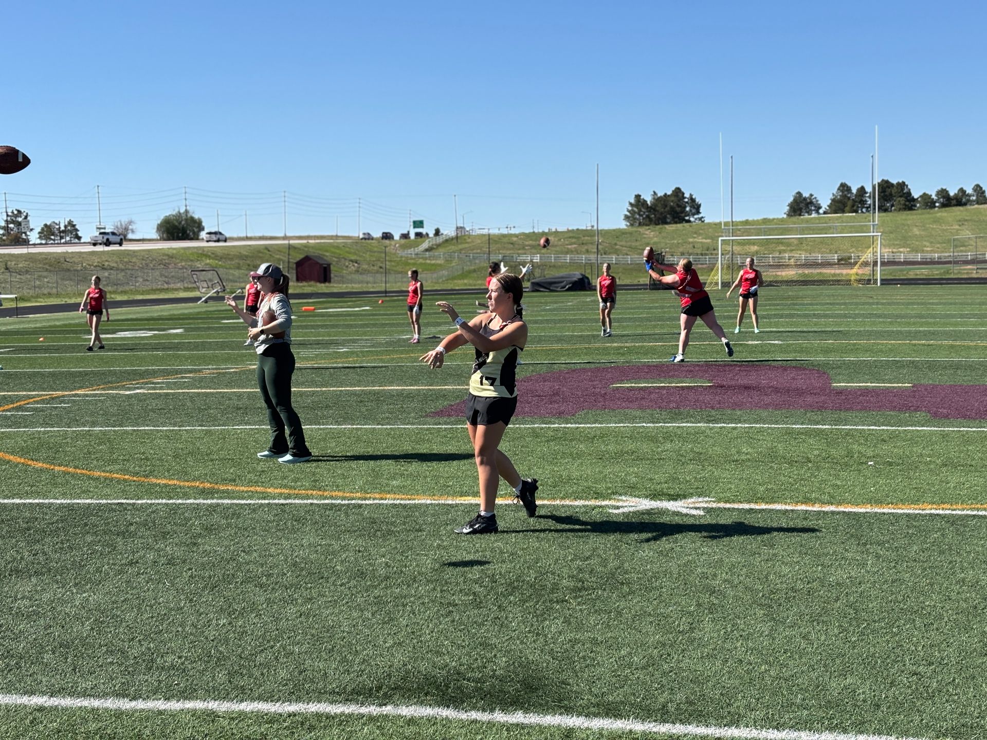 Flag Football players in red and black on a green field during a game