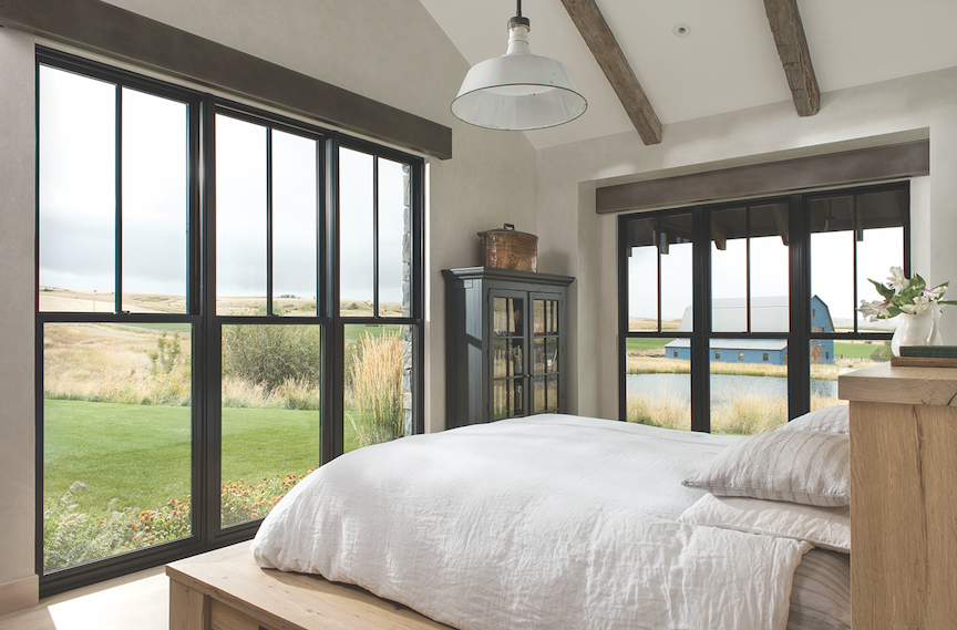 A bedroom with a large bed and lots of windows.