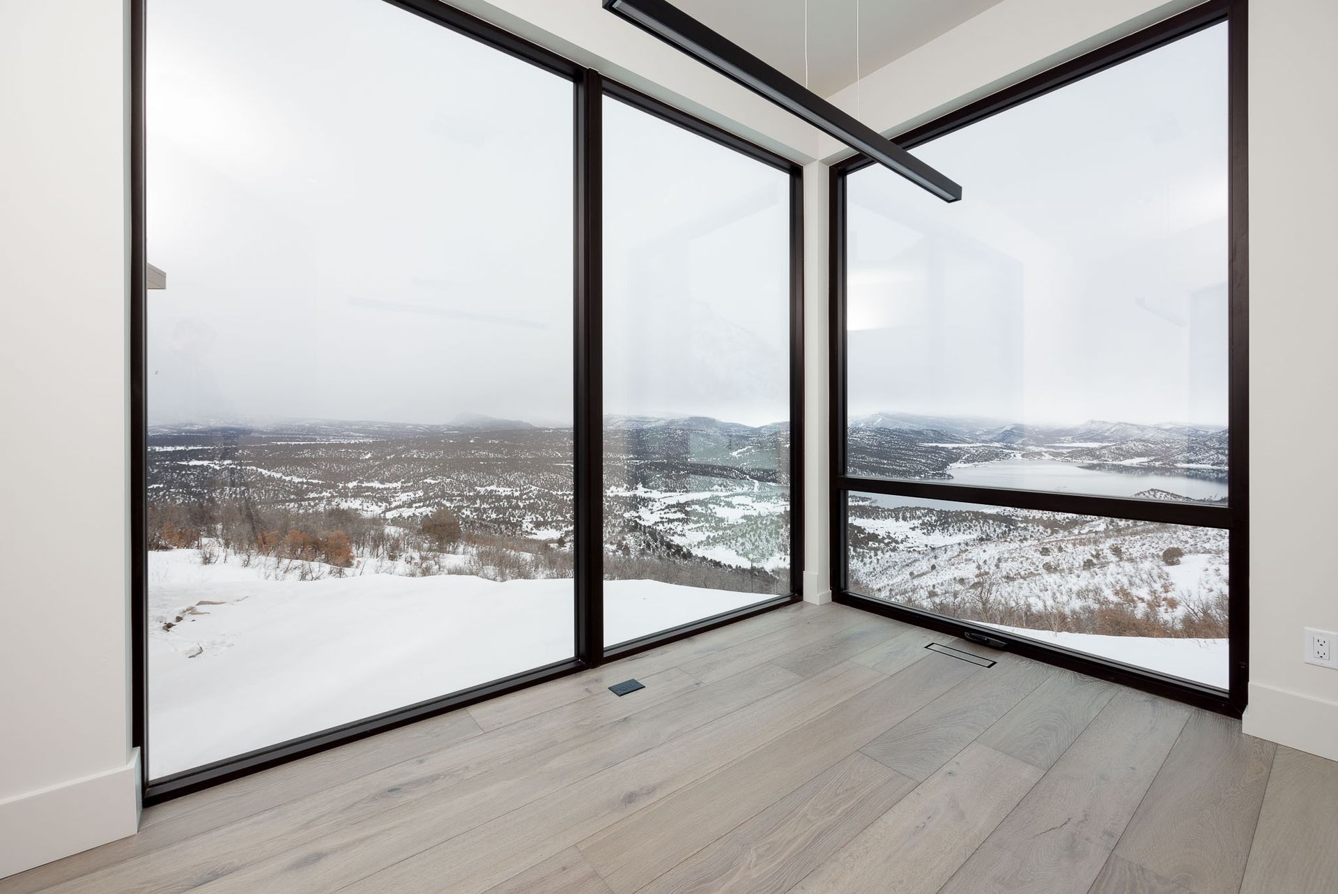 A room with a lot of windows and a view of a snowy landscape.