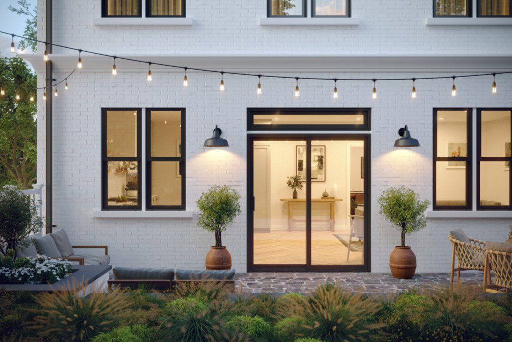 The backyard of a white house with a patio and sliding glass doors.