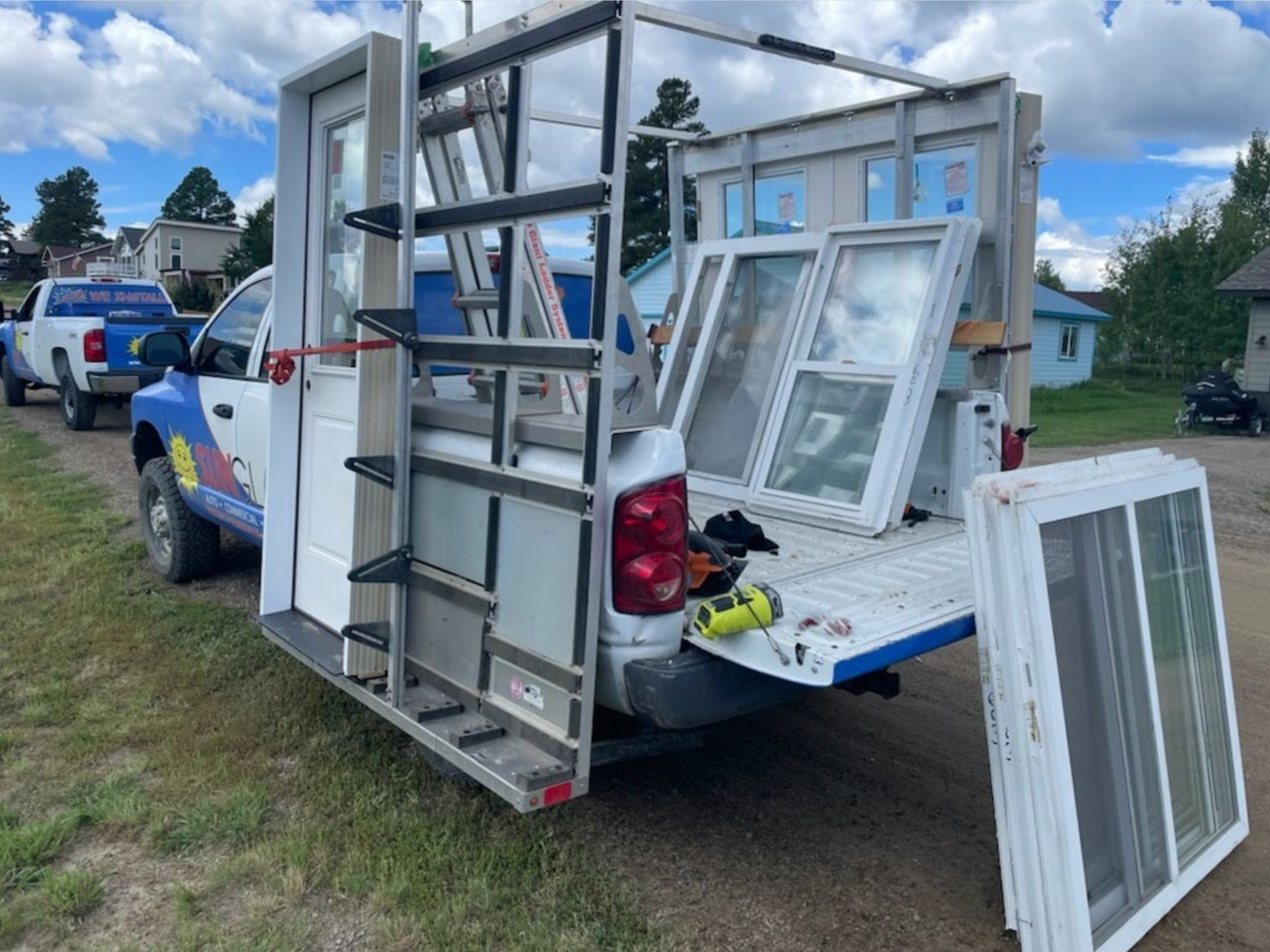 A truck with a ladder on the back is loaded with windows.
