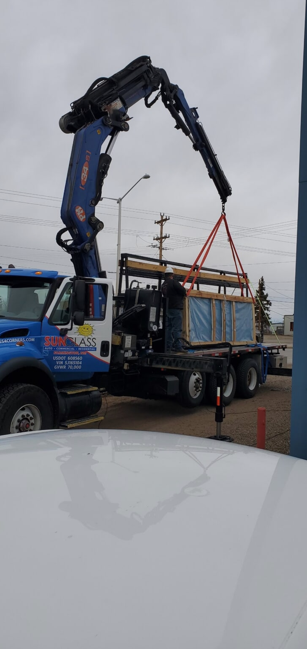A truck with a crane attached to it is lifting a box.