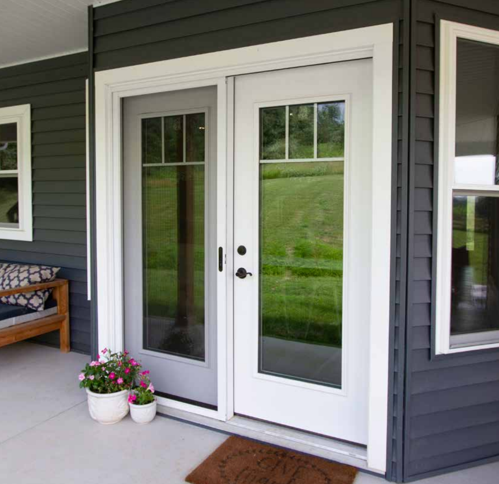 A gray house with a white door and a welcome mat