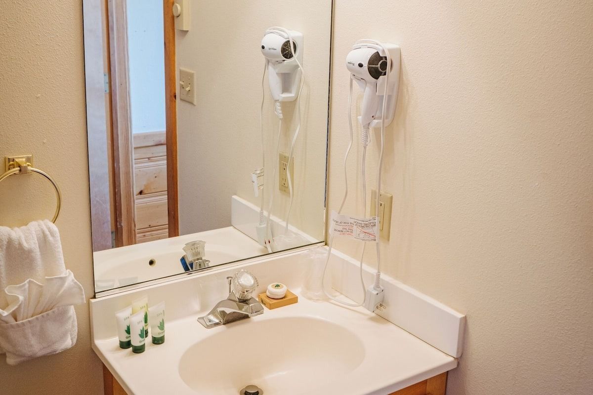 Bathroom with mirror, sink, hairdryer, and toiletries.