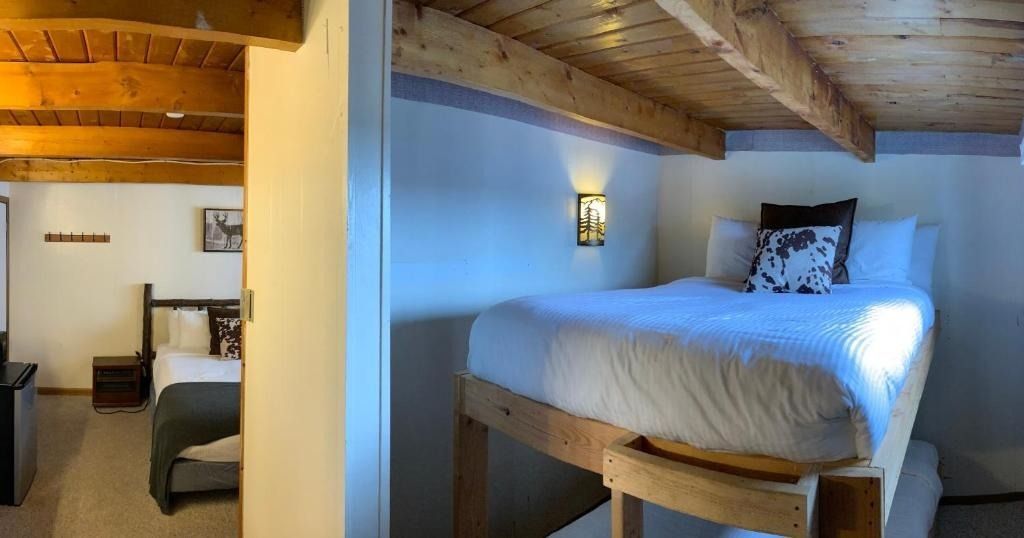 Bedroom with elevated bed platform. Exposed wooden beams, white walls, double bed in the background.