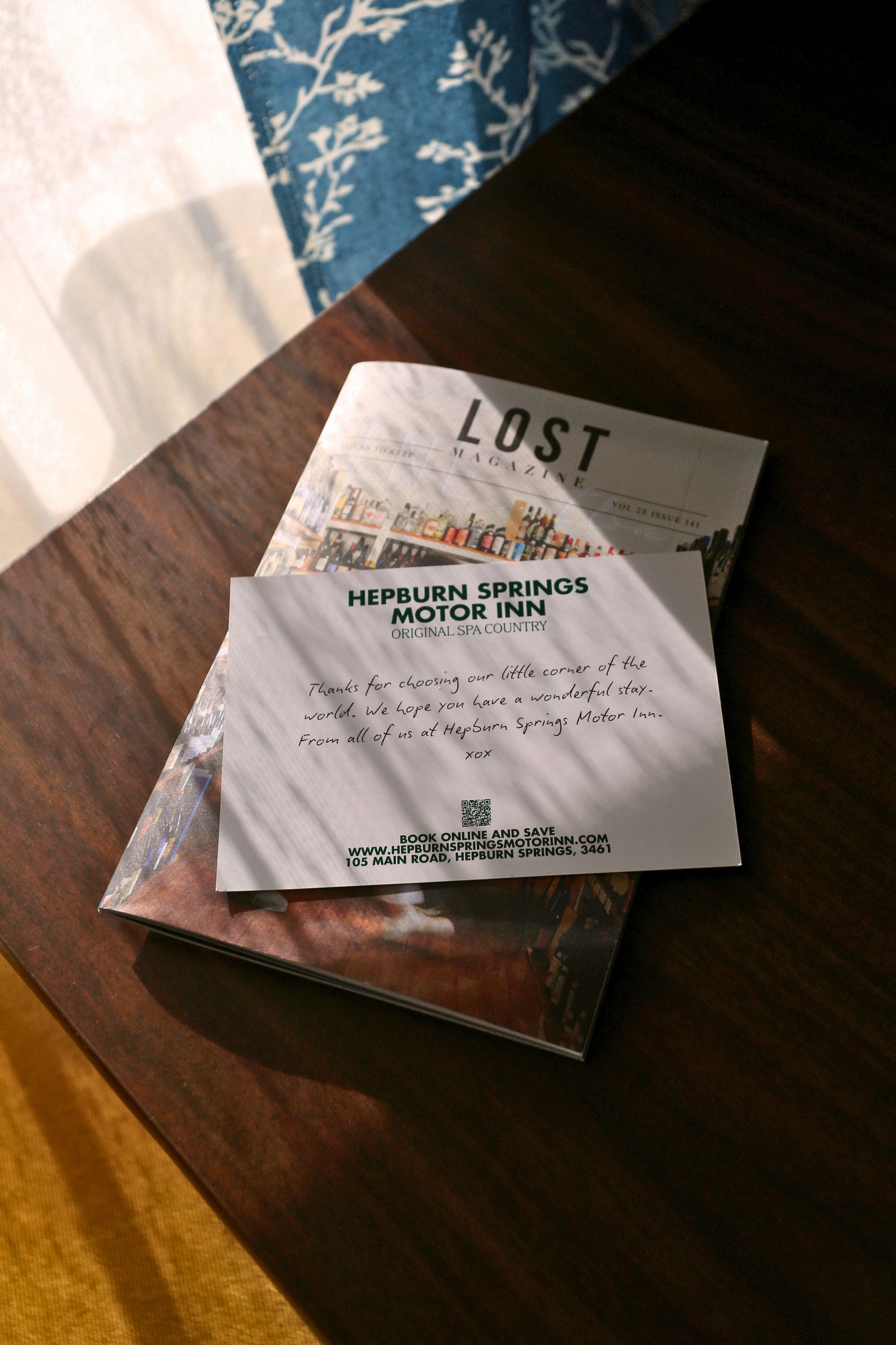 A brochure and a hotel card on a brown table; the card reads 