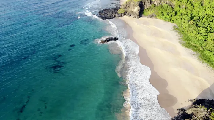 Uma vista aérea de uma praia com ondas quebrando na costa.