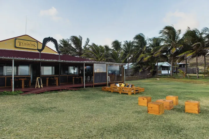 Um prédio amarelo com um telhado vermelho está situado no meio de um campo gramado.