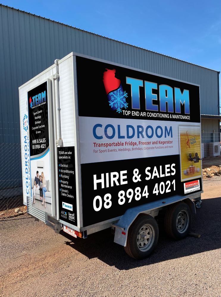 Trailer with TEAM Coldroom Hire & Sales signage parked beside a warehouse under a blue sky