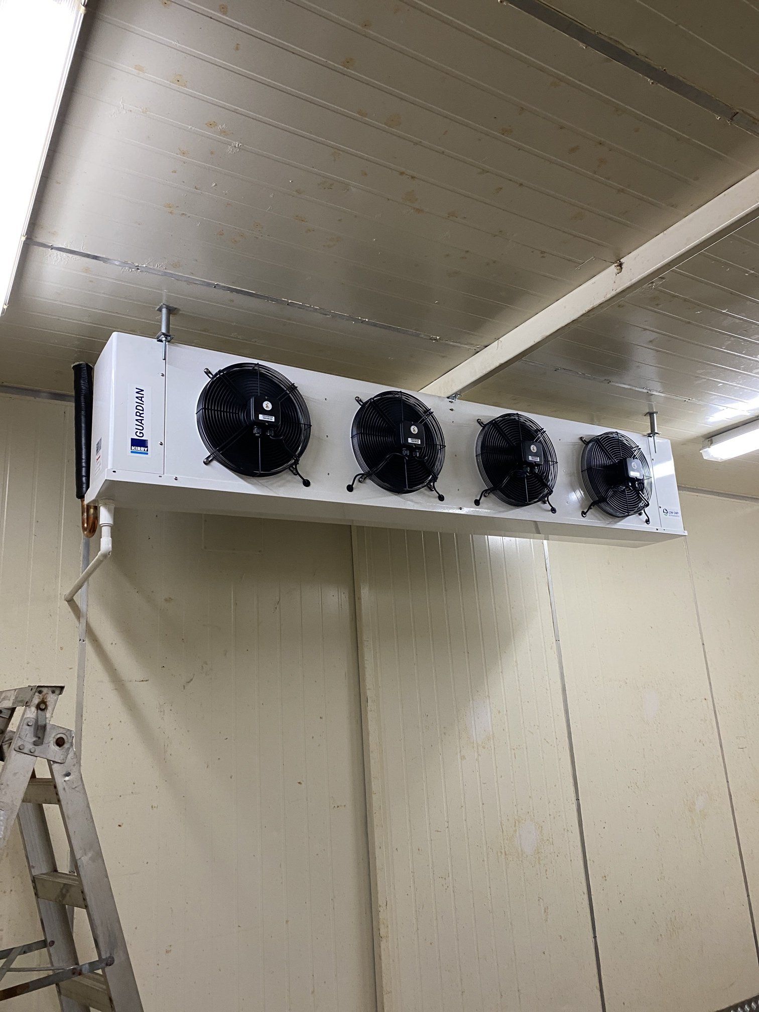Large white industrial refrigeration unit with four black fans mounted near the ceiling.