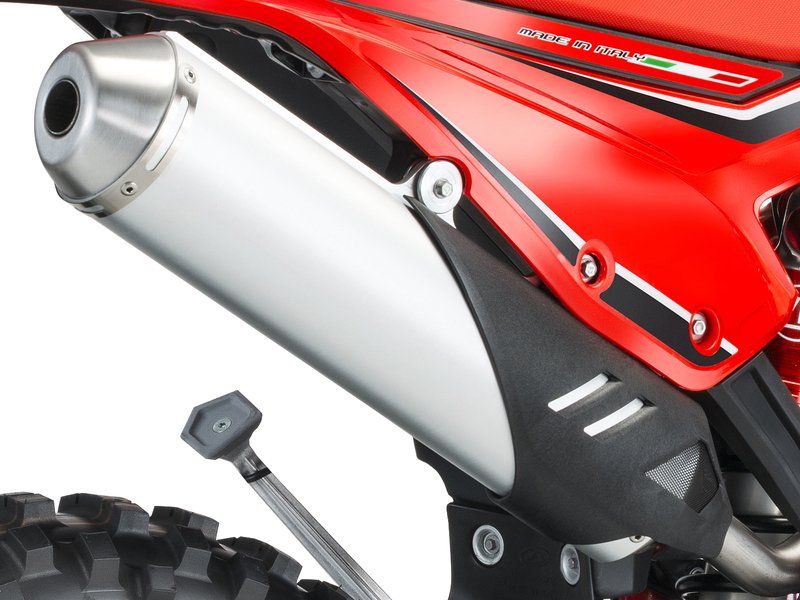 A red dirt bike with a stainless steel exhaust pipe
