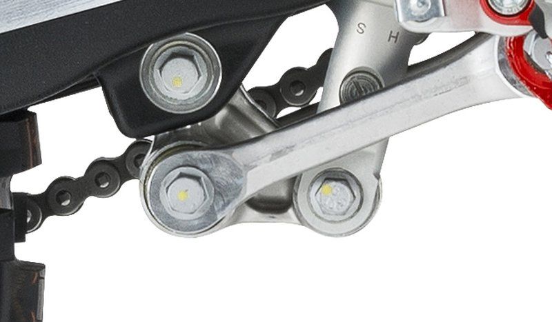 A close up of a motorcycle chain with a wrench attached to it.