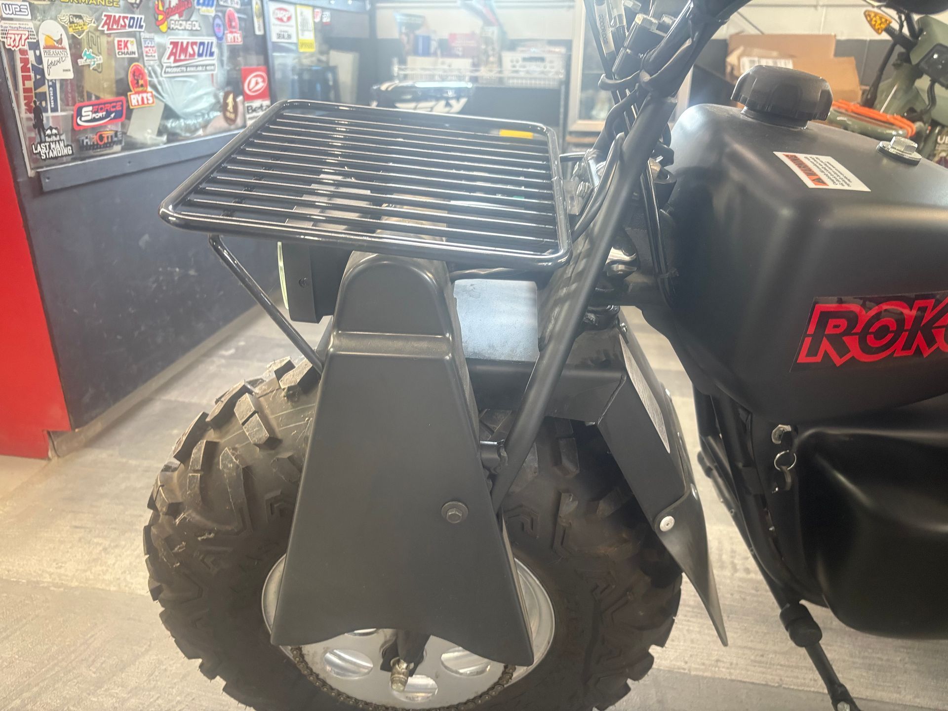Black ATV with front cargo rack and large tires inside a workshop.