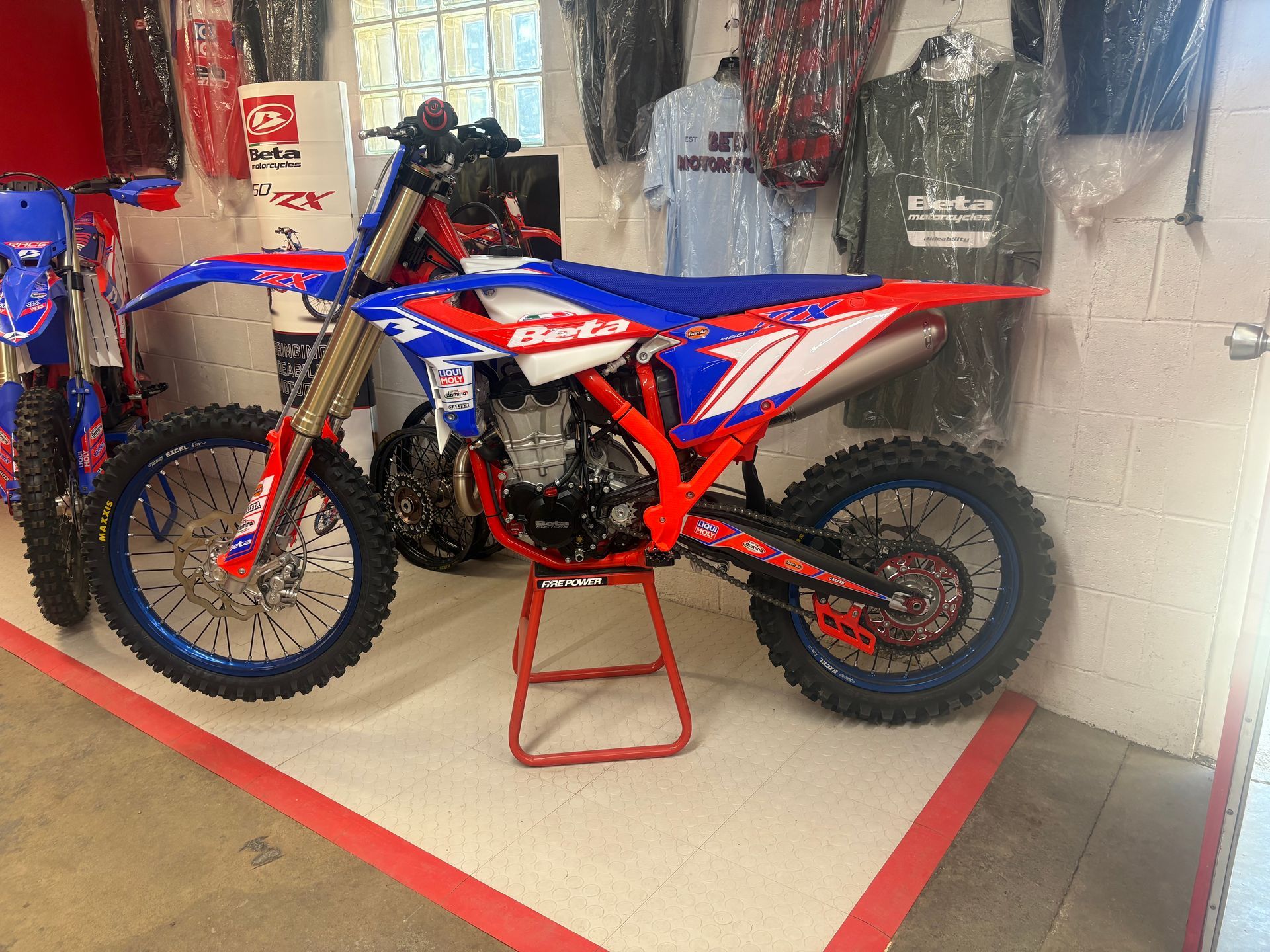 Red and blue motocross bike on a stand in a showroom display.