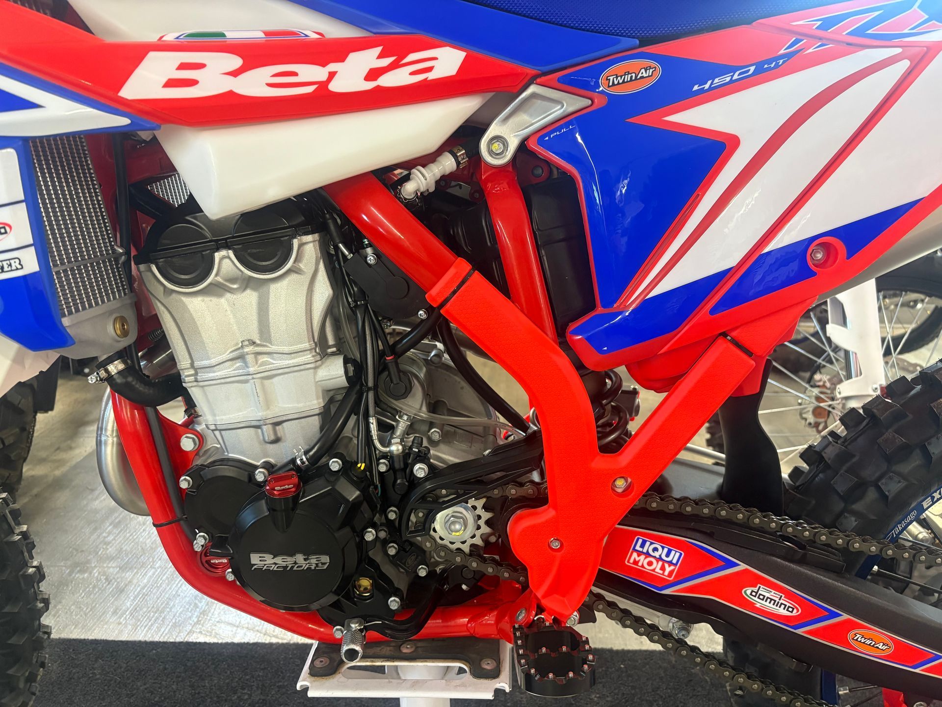 Close-up of a blue and red Beta dirt bike frame and engine with knobby rear tire