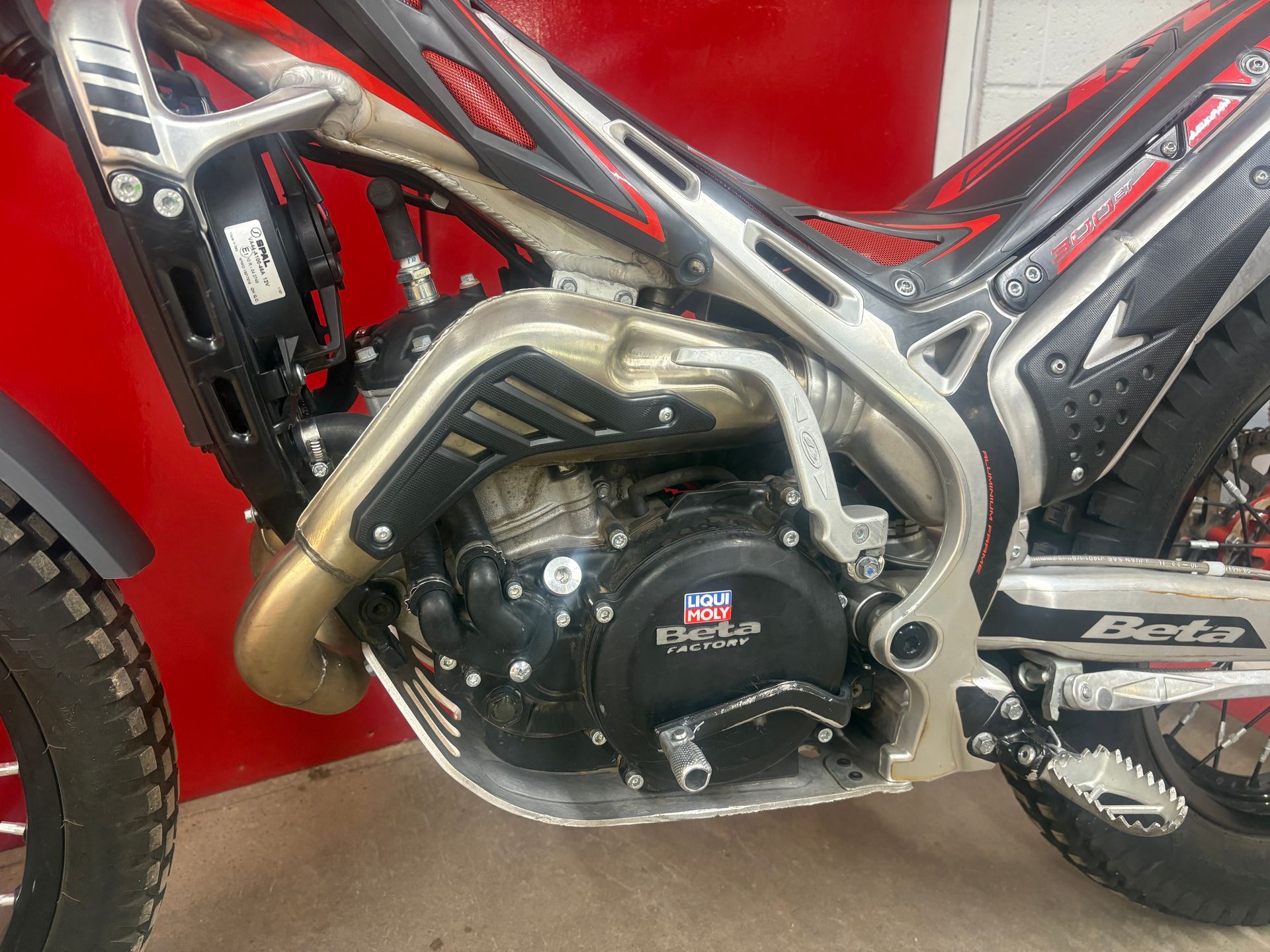Close-up of a red off-road motorcycle engine with a silver exhaust and black frame