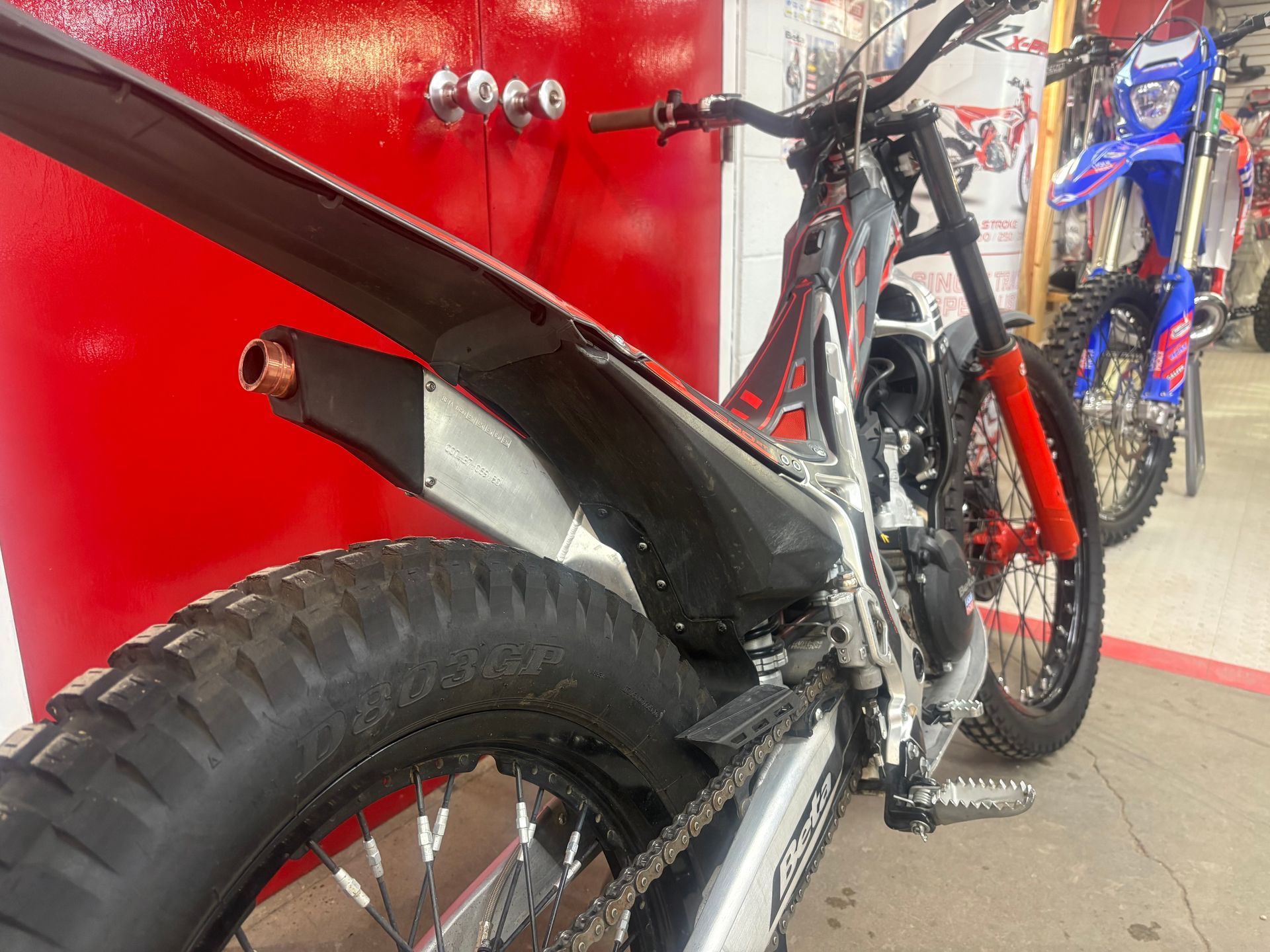 Close-up of a black mountain bike with red accents parked indoors by a red wall.