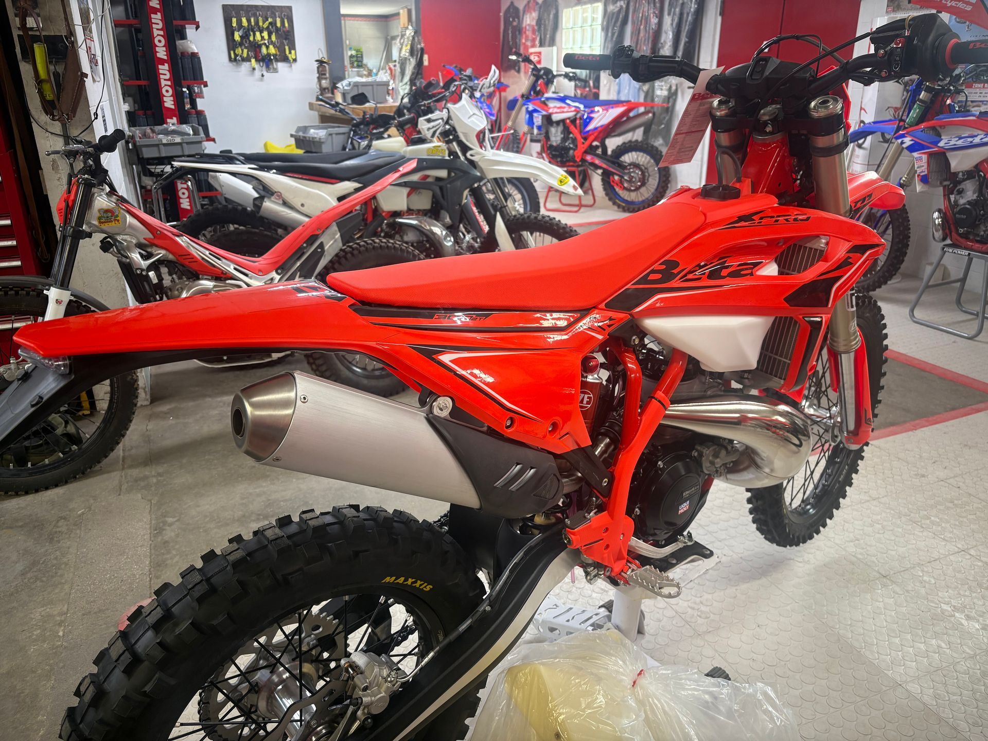 Red dirt bike in a showroom, side view, with bright red bodywork and knobby tires.