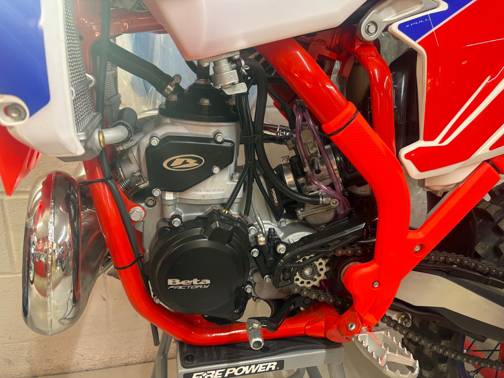 Close-up of a red dirt bike engine and frame with white and blue body panels