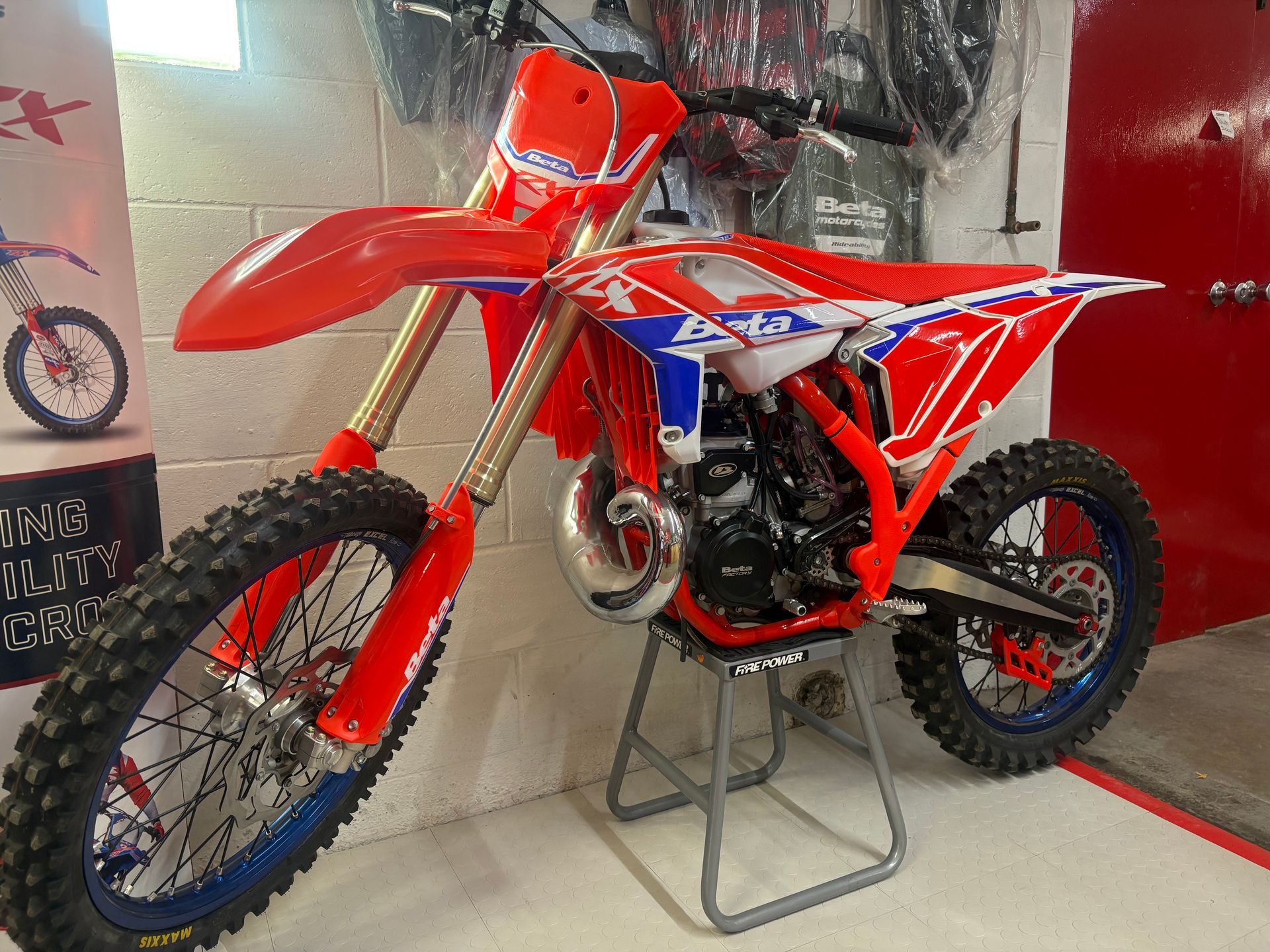 Red dirt bike on a display stand in a showroom, with red and white bodywork and knobby tires