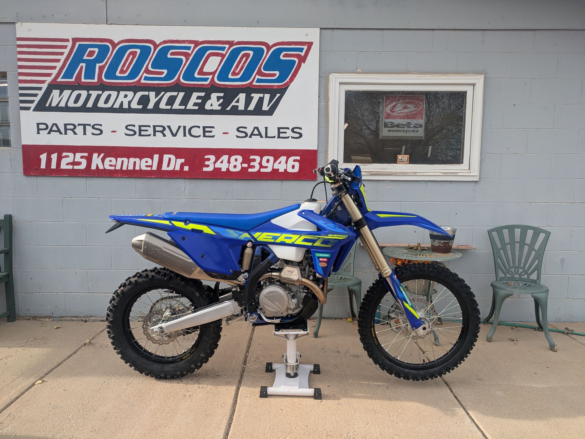 Blue dirt bike on a stand outside Rosco’s Motorcycles ATV parts and service shop.