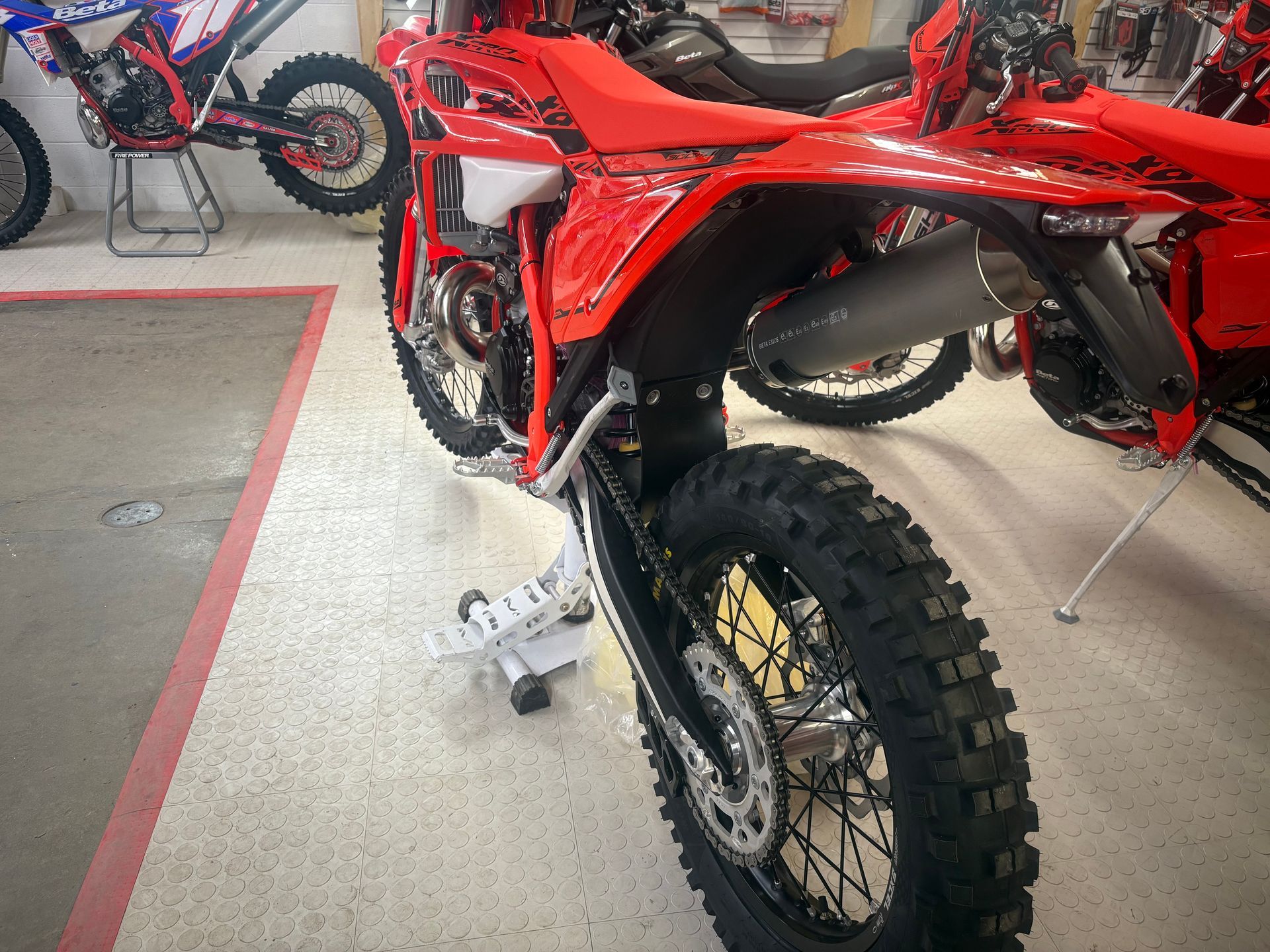 Red dirt bike in a showroom, side view with knobby tires and red bodywork.