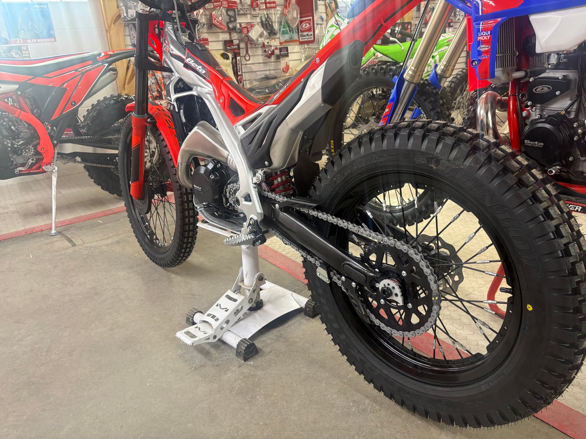 Red and black mountain bike on a stand in a bike shop, close-up of the drivetrain and rear wheel.