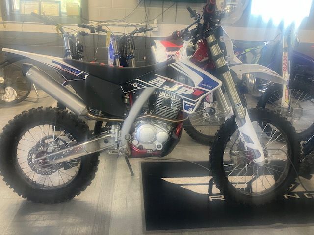 A dirt bike is sitting on a mat in a garage.