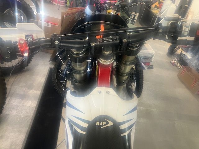A white and red dirt bike is parked in a garage.