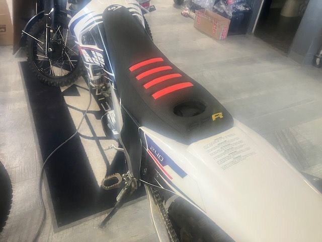 A white dirt bike with red stripes on the seat