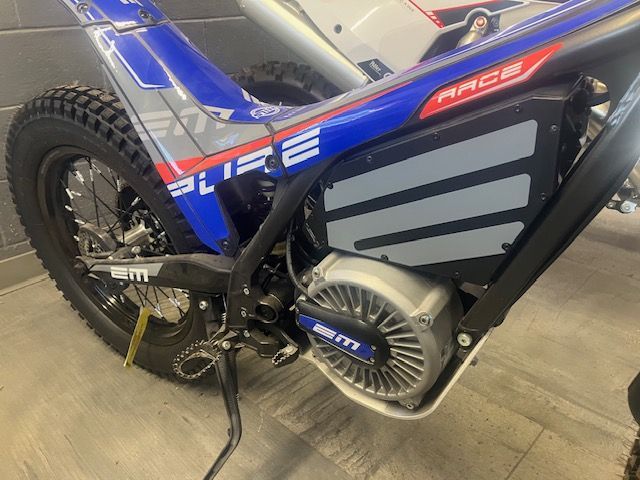 A blue and red dirt bike is parked in a garage.