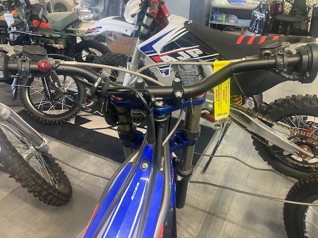 A blue and white dirt bike is sitting in a showroom.