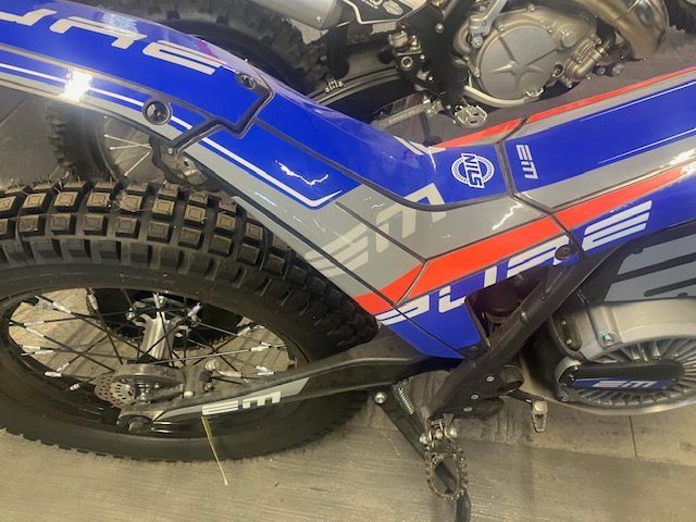 A blue and red dirt bike is parked in a garage.
