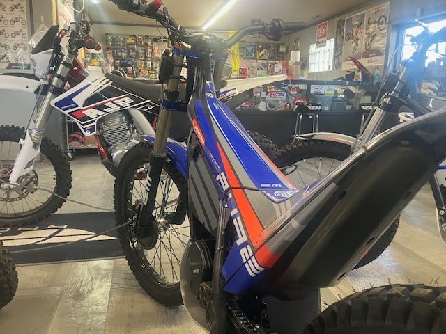 A blue and white dirt bike is parked in a garage.