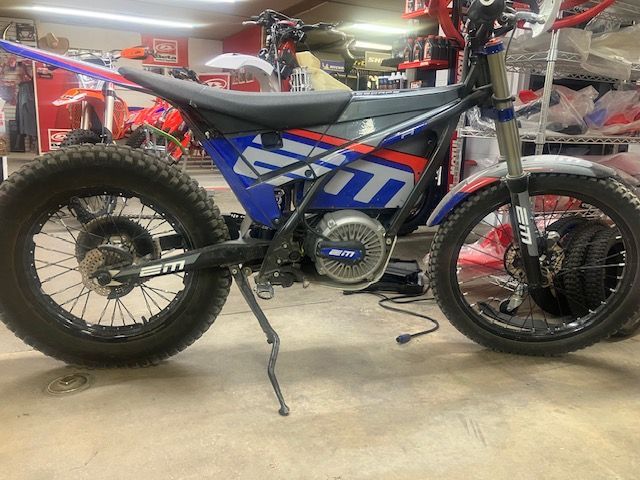A blue and red dirt bike is parked in a garage.