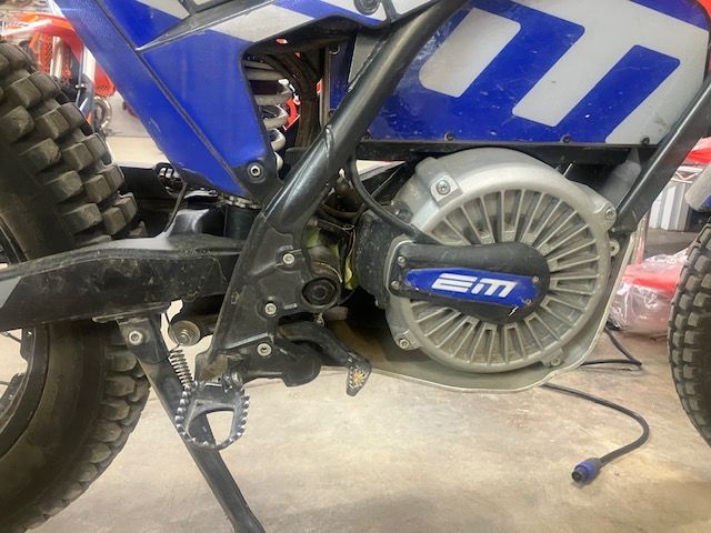 A blue and white dirt bike with the word em on the engine