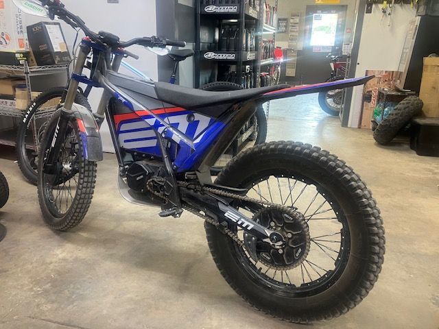 A blue and red dirt bike is parked in a garage.