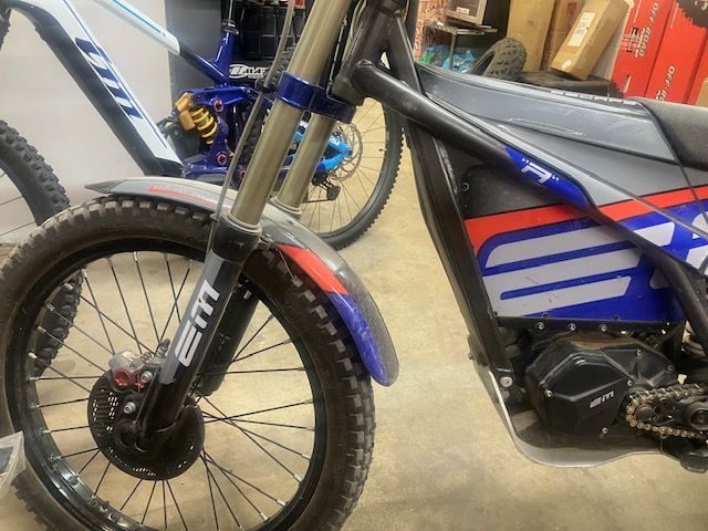 Two dirt bikes are parked next to each other in a garage