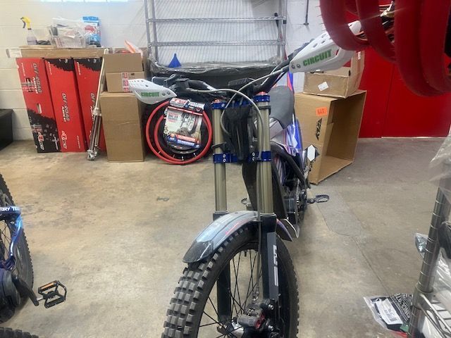 A dirt bike is parked in a garage surrounded by boxes.