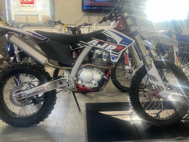 Two dirt bikes are parked next to each other in a garage.