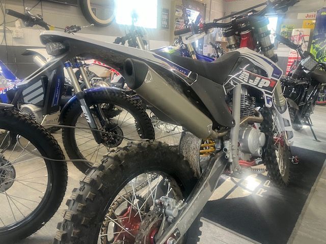 A dirt bike is parked in a garage next to other dirt bikes.