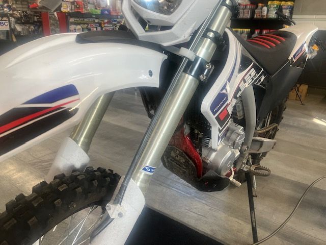 A white dirt bike is parked in a garage