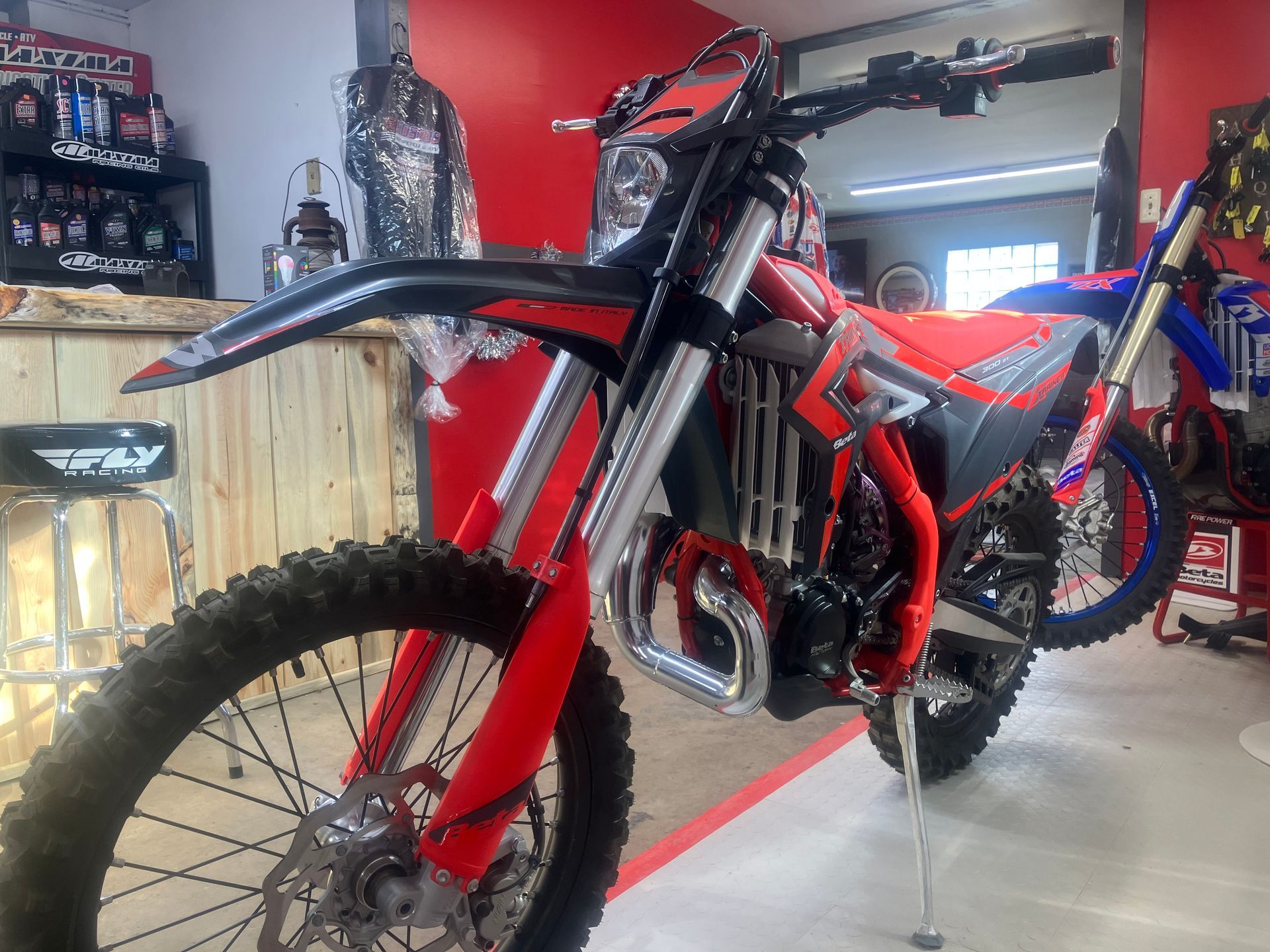 A red and black dirt bike is parked in a garage.
